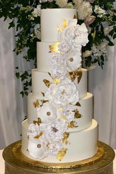 a white and gold wedding cake with flowers on top