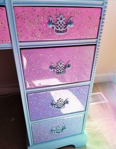 a pink and blue dresser with glitter on the drawers