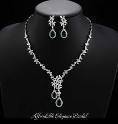 a necklace and earring set on a mannequin with diamonds, emeralds and pearls