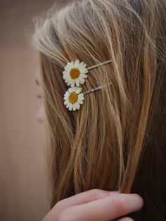 a close up of a person's hair with two daisies in the middle