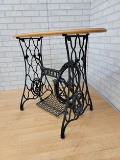 an old fashioned sewing machine sitting on top of a wooden table next to a brick wall