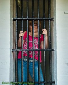 a woman standing behind bars in a jail cell