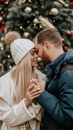 a man and woman standing in front of a christmas tree