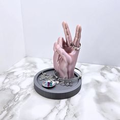 a hand that has been placed on top of a marble surface with jewelry around it