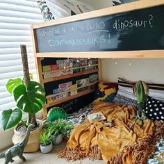 a child's bed with a chalkboard above it and plants on the floor