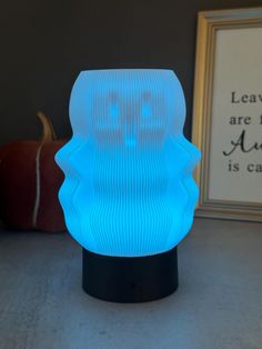 a blue light sitting on top of a table next to a framed photo and pumpkins