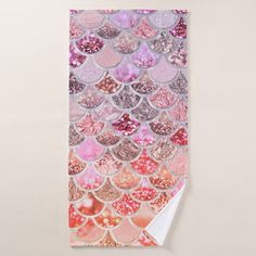 a pink and gold mermaid scale pattern towel hanging on a wall with white paper underneath it