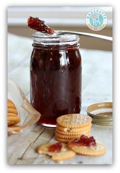 a jar filled with jelly and crackers next to some cookies on a table top