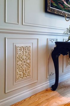 an ornate console table in the corner of a room with white walls and wood floors