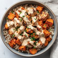 a bowl filled with rice and chicken covered in gravy, garnished with parsley