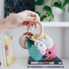 a person holding a baby toy in their hand on top of a white table next to books