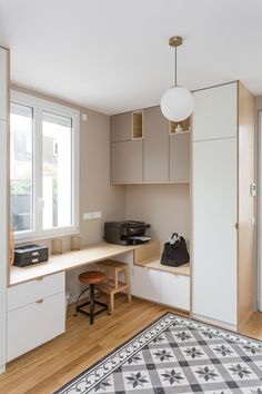 a room with a rug, desk and cabinets on the floor in front of two windows