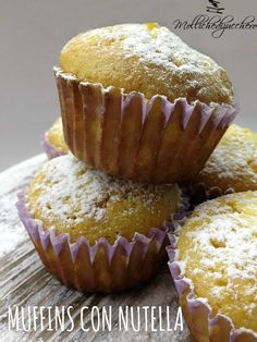 muffins with powdered sugar on top are sitting on a wooden surface and stacked up