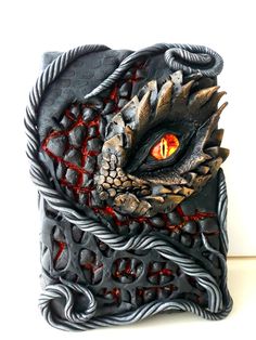 a close up of a dragon's eye on a piece of art that looks like it has red eyes