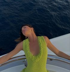 a woman in a bright green dress is sitting on a boat looking up at the sky