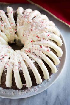 a chocolate cake with white icing and sprinkles on a glass plate