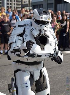 a man dressed as a stormtrooper walking down the street in front of a crowd