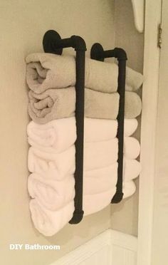 several folded towels are hanging on the wall in a bathroom with two black towel racks