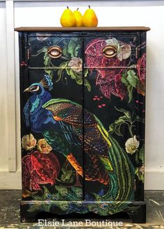 an ornate painted cabinet with two oranges sitting on it's top and bottom