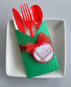 a green gift box with red utensils and a tag on it that says merry christmas