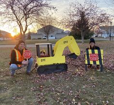 two people sitting in the grass with construction equipment