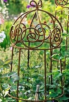 an iron birdcage in the middle of a garden