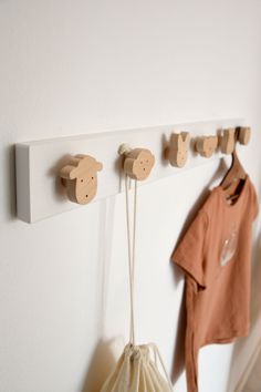 three wooden pegs are hanging on the wall next to a bag and coat rack