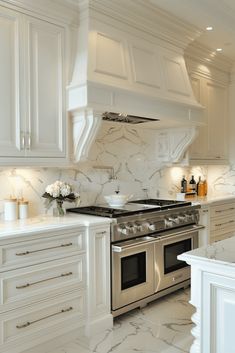 a kitchen with white cabinets and marble counter tops, stainless steel stove top oven and range