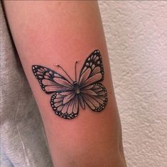 a black and white butterfly tattoo on the arm