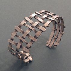 This bracelet is a comprised of a loose network of irregular blackened silver bars. The light, open design and partial darkness of the silver make this ring a classic and exciting piece of jewellery. The bracelet alone is very impressive, but it is also well suited in combination with other pieces from the “Lattice collection. These items and more can also be ordered from our jewellery factory's online shop. . silver - material information. Dimensions: Bracelet width: 1.06 inch, 27 mm Modern Hand Forged Metal Bracelet, Modern Cuff Bracelet With Oxidized Finish, Modern Oxidized Cuff Bracelet Bangle, Modern Oxidized Finish Cuff Bracelet Bangle, Modern Oxidized Finish Cuff Bangle Bracelet, Open Design, Silver Bars, Photo Bracelet, Lattice