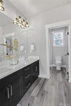 a bathroom with wood floors and white walls