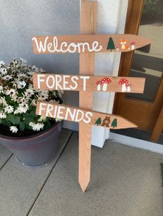 a wooden sign that says welcome forest friends next to a potted plant with flowers