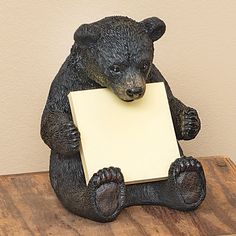 a statue of a bear holding a piece of paper on top of a wooden table