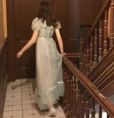 a woman in a long dress is walking down the stairs