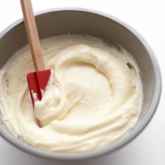 a red spatula in a white bowl filled with cream