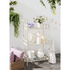 a white shelf filled with lots of vases next to a plant and potted plants