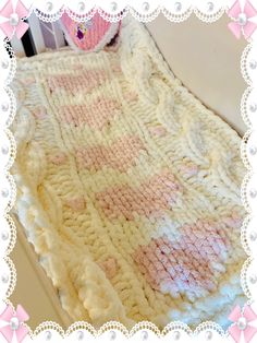 a crocheted blanket with pink and white designs