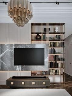 a living room with a large tv and bookshelves on the wall, in front of a chandelier