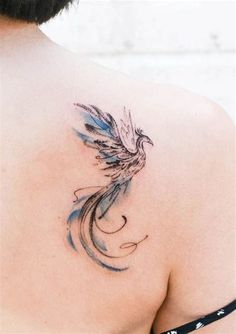 the back of a woman's shoulder with a bird tattoo on her left side