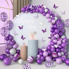 a birthday cake surrounded by purple and white balloons in front of a sign that says happy day