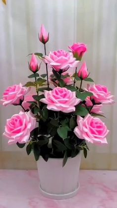 a white vase filled with pink roses on top of a table