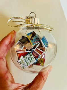 a hand holding a glass ornament filled with lots of stickers