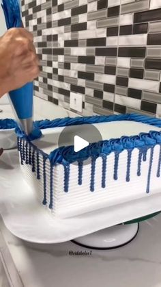 someone cutting a cake with blue icing on it