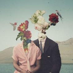 two people with flowers on their heads sitting next to each other in front of the ocean