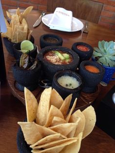 a table topped with different types of food and dipping sauces on top of tortillas