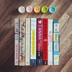 a row of books sitting next to each other on top of a wooden floor in front of candles