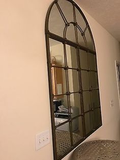 an arched mirror hanging on the wall above a stool in a room with white walls