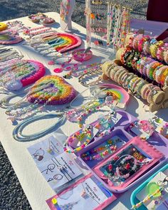 a table topped with lots of beads and bracelets on top of a white table cloth