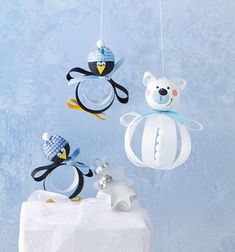 three penguin ornaments hanging from strings on a blue background