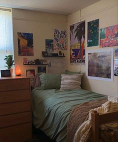 a bed sitting in a bedroom next to a window with pictures hanging on the wall